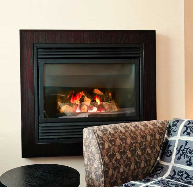 Fireplace insert in wall with sofa and stool in the foreground