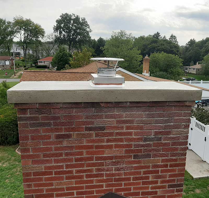 Beautiful chimney crown after restoration trees and homes in the background