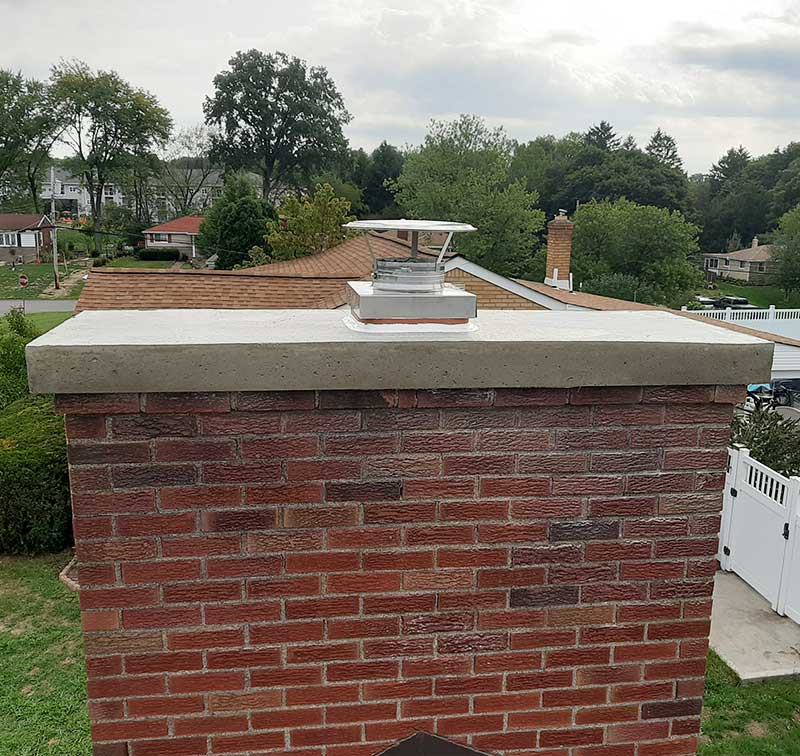 Original photo of chimney crown after restoration - Top Cat Chimney - Cowansville, PA Beautiful chimney crown after restoration trees and homes in the background