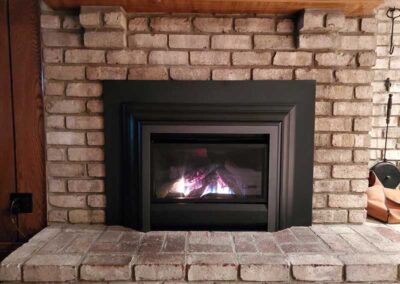Gas insert with beautiful wood mantle tools to the right and old brick surround and hearth.