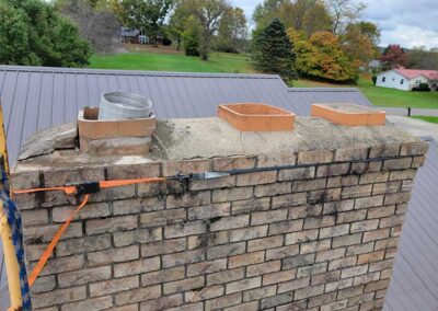 Chimney Crown before replacement with three flues - one has a liners sticking out the top - homes and trees in the background.