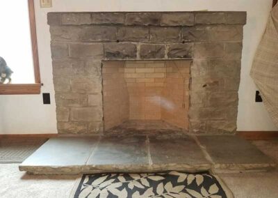 PriorFire Firebox before cleaning with rock surround and a kitty in the window to the left.