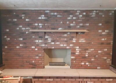 Ahren-Fire Firebox With Masonry after repair - beautiful redbrick with white spashes throughout. Wooden mantel granite hearth.