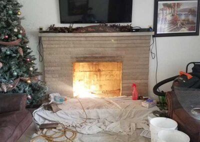 Ahren-Fire Firebox Before installation with Christmas tree to the left and picture to the right. There is a tarp and buckets covering the floor.