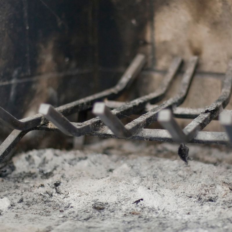 a fireplace grate and a firebox with a bed of ash underneath